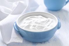 a blue bowl filled with whipped cream on top of a white cloth next to a blue cup