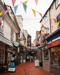 the street is lined with shops and decorated with colorful buntings on each side