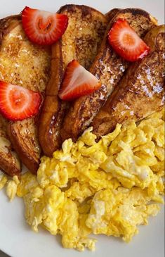 eggs, strawberries, and toast on a plate with scrambled eggs next to it