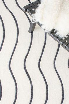 a white rug with black lines on it and a furry animal sitting on top of the rug