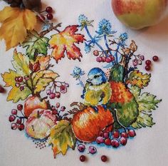 a cross - stitch pattern with fruit and leaves on the table next to it is an apple