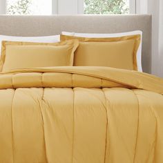 a bed with yellow sheets and pillows in a bedroom