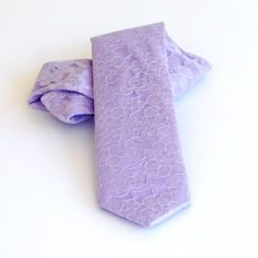 a purple tie is laying on top of a white surface with two pieces of cloth folded around it