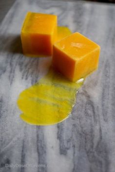 two cubes of cheese sitting on top of a table next to oil and wax