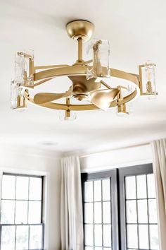 a chandelier hanging from the ceiling in a living room with windows and curtains