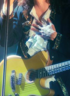 a woman holding a yellow guitar in front of a microphone