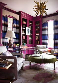 a living room filled with lots of furniture and bookshelves covered in purple curtains