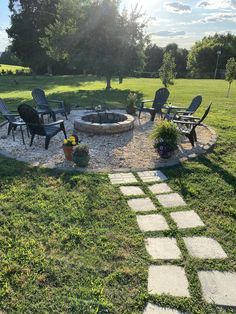 an outdoor fire pit surrounded by chairs and lawn furniture in the back yard with grass