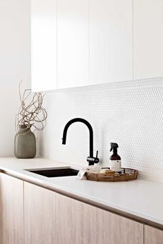 a kitchen sink sitting under a window next to a faucet and soap dispenser