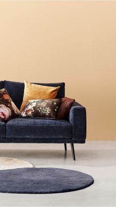 a blue couch sitting on top of a white rug in a living room next to a beige wall