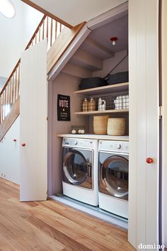 a washer and dryer in a small room with stairs leading up to the second floor