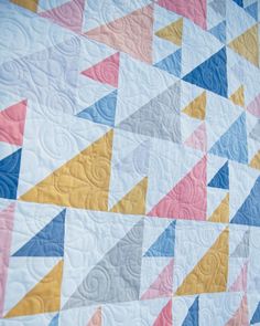 a quilted wall hanging with colorful triangles on it