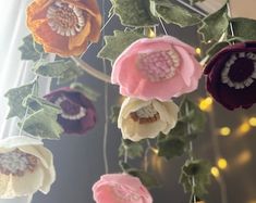 an arrangement of flowers hanging from a window sill with string lights in the background