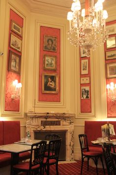 a dining room with red booths and chandelier hanging from the ceiling, along with pictures on the walls