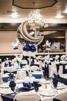 the table is set up with blue and white linens, silverware, and balloons