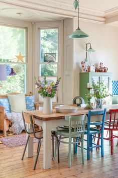 a dining room table with four chairs in front of it and a window behind it