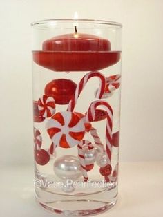 a candle that is inside of a glass with candy canes and candies in it