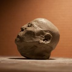 a stone head sitting on top of a wooden table next to a wallpapered brown background