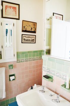 a bathroom with green and pink tiles on the walls, sink and mirror above it