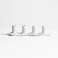 four white ceramic candlesticks sitting on top of each other in front of a white background