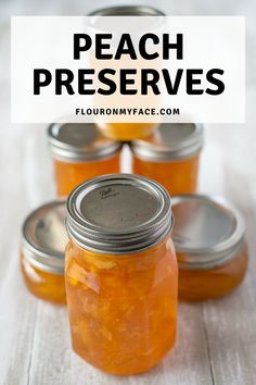 four jars filled with peach preserves sitting on top of a white wooden table and text overlay reads peach preserves