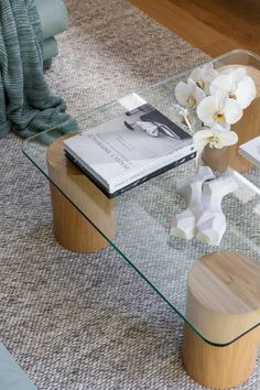 a glass table with some flowers on it and a book in the middle next to it