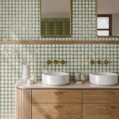 two white sinks sitting on top of a wooden cabinet next to a wall mounted mirror