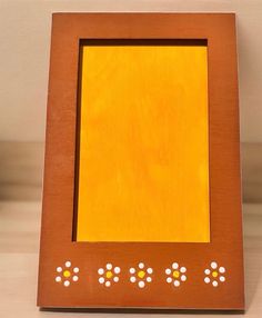 a wooden frame with white and yellow dots on the edges is sitting on a table