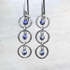 "These dangle earrings are created from genuine blue Lapis Lazuli gems and sterling silver.  The tiny natural stones are framed by a set of sterling silver circular rings.  I have created the rings by forming, soldering, and hammering them by hand.  The drops dangle from handmade sterling silver earwires.  The silver has been oxidized and polished to create an antique patina finish. Be sure to see all photos and video for size and color reference.   Lapis Lazuli: About 3.5mm Total Earring Length (Including Earwire): About 1.75\" Total Earring Weight: About 1.5 grams per one earring  Wise Handmade Jewelry is an eco-conscious company.  Jewelry will be carefully packaged in earth-friendly and sustainable materials. For more information about Wise Handmade Jewelry, visit wisehandmade.com" Blue Sterling Silver Hoop Earrings Nickel-free, Blue Sterling Silver Hoop Earrings Nickel Free, Lapis Lazuli Dangle Earrings With Matching Jewelry, Lapis Lazuli Dangle Earrings Jewelry Set, Sapphire Dangle Earrings With Natural Stones, Sapphire Dangle Earrings In Sterling Silver, Sapphire Sterling Silver Hoop Earrings For Gift, Sapphire Dangle Jewelry With Natural Stones, Sapphire Sterling Silver Hoop Earrings As Gift