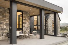 an outdoor patio with chairs and tables on the concrete floor next to a stone building