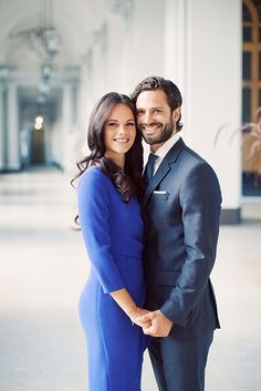 a man in a suit and tie standing next to a woman wearing a blue dress