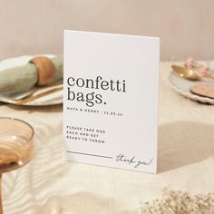 a table topped with plates and napkins covered in confetti bags on top of a table cloth