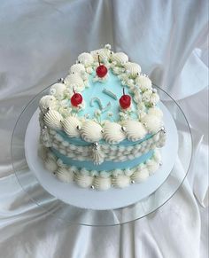 a cake with white frosting and cherries on top sitting on a glass platter