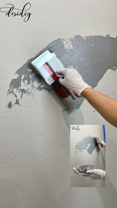 a person using a brush to paint a wall with gray paint and white gloves on