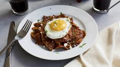 a plate with waffles and an egg on top, next to two glasses of soda