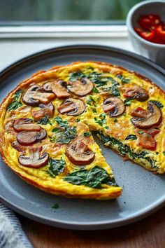 an omelet with mushrooms and spinach is on a plate next to a cup