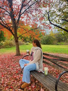 a woman sitting on a park bench holding a cup