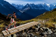 a man running across a wooden bridge in the mountains