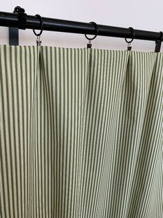 green and white striped curtain with black metal rod ends hanging from the side of a window