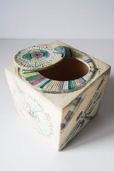 an artisticly designed ceramic container on a white surface