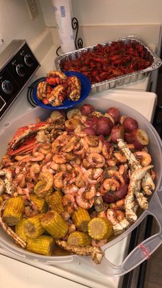 a large platter filled with shrimp, corn and potatoes next to other food items