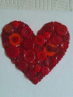 a heart made out of buttons sitting on top of a white table next to a wall