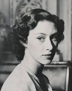 an old black and white photo of a woman with pearls on her neck, looking at the camera