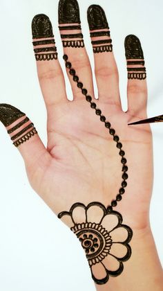 a hand with henna tattoos on it and a black beaded bracelet attached to the wrist