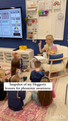 a group of children sitting on the floor in front of a tv with a teacher talking to them