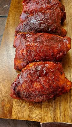 two pieces of meat sitting on top of a wooden cutting board