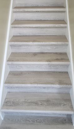 a set of white stairs with wood treads in the middle and light brown flooring on both sides