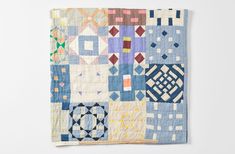 a quilt is hanging on the wall in front of a white background with an abstract design