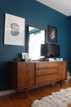 a living room with blue walls and a wooden dresser next to a tv on top of it