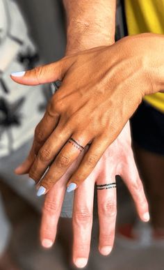 two people holding each other's hands with tattoos on their fingers